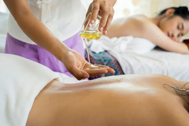 Spa therapist pouring warm oil for a back massage at Tèya Beach Hotel