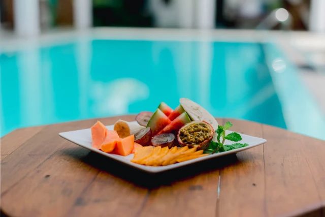 Fresh tropical fruit platter with papaya, watermelon, banana, and passionfruit by the pool