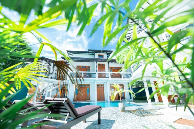 Tèya Beach Hotel's pool and sun loungers framed by tropical palm leaves
