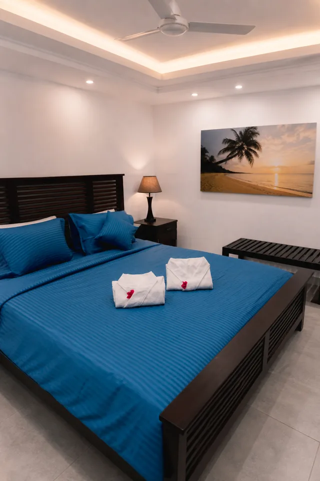 Double room with blue bedding and a framed beach print above the headboard