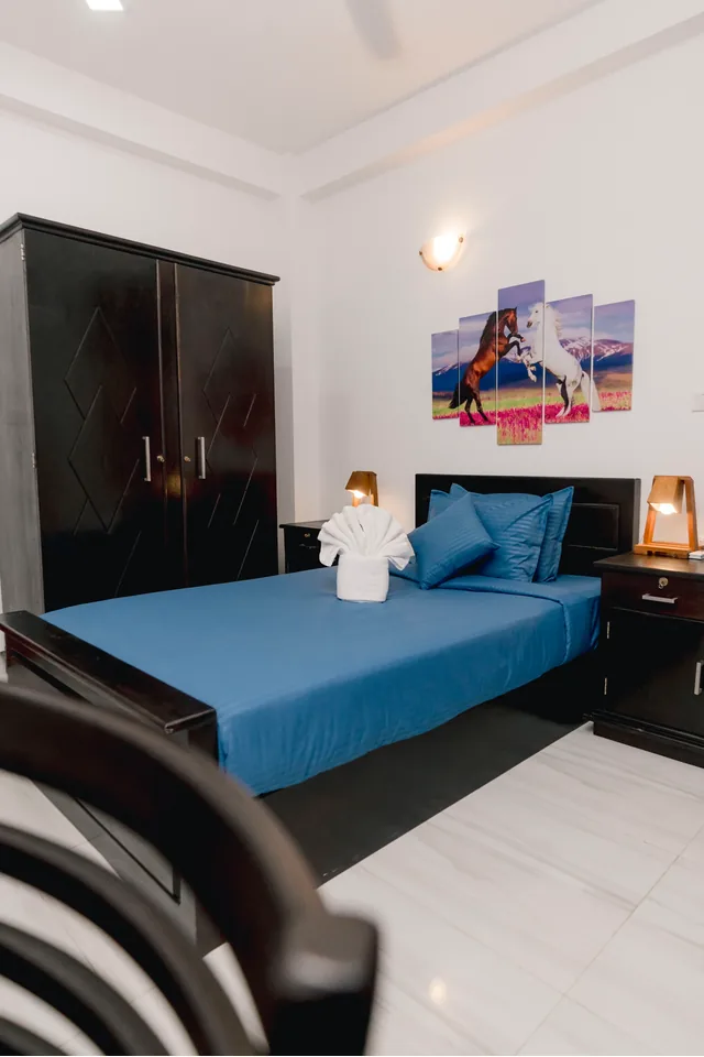 Room with blue bedding, rearing-horses artwork, and doors open to the pool deck