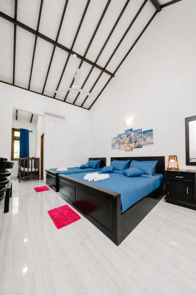 Room with blue bedding and doors opening onto a private balcony with garden views
